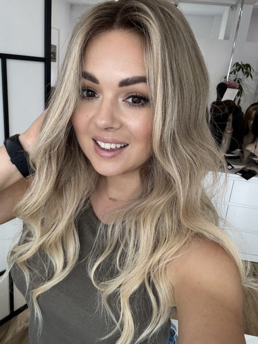 Peruka Daisy 55 cm z naturalnych włosów w kolorze ciepły blond ombre, założona na głowie, z przedziałkiem ustawionym na środku, lace front i realistyczną linią włosów.
