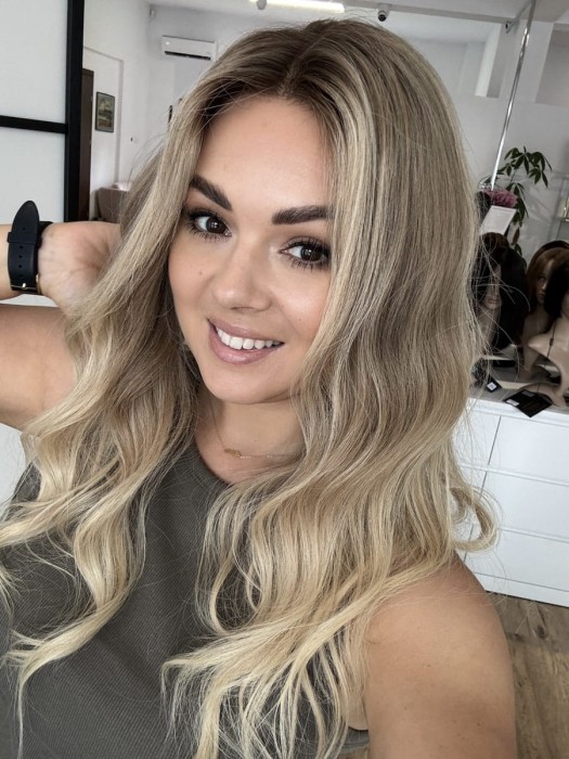 Peruka Daisy 55 cm z naturalnych włosów w kolorze ciepły blond ombre, założona na głowie, z przedziałkiem ustawionym na środku, lace front i realistyczną linią włosów.