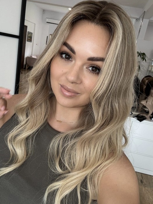 Peruka Daisy 55 cm z naturalnych włosów w kolorze ciepły blond ombre, założona na głowie, z przedziałkiem ustawionym na środku, lace front i realistyczną linią włosów.